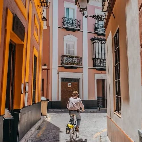 A man cycling through a typical Sevillian street