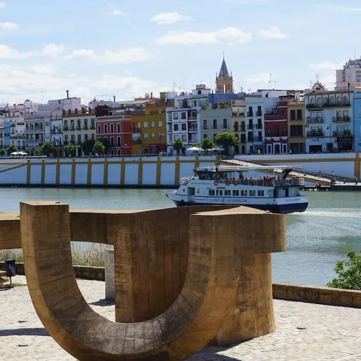 Sculpture next to the river with a boat passing by