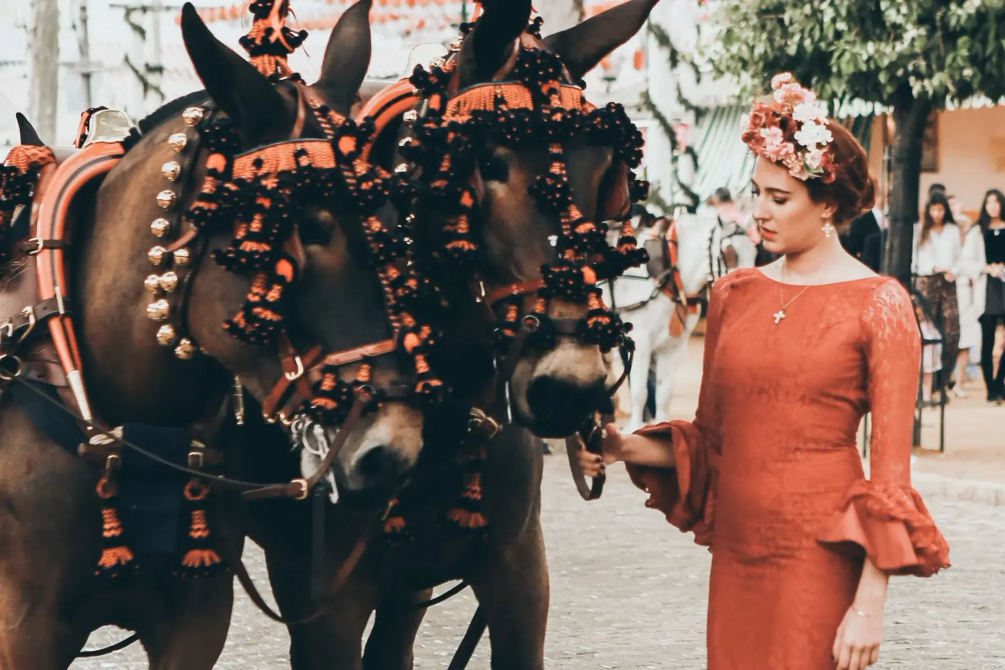 A woman dressed in traditional clothing next to two decorated horses during the April Fair